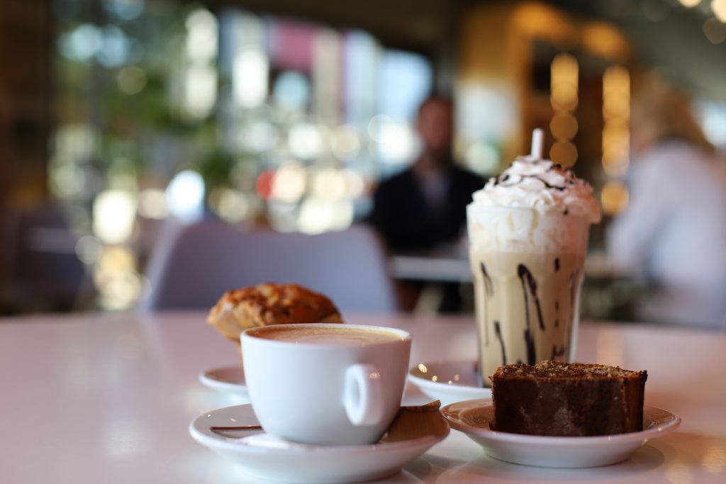 focus sur une tasse de café une part de gâteau et un latte chantilly sur une table